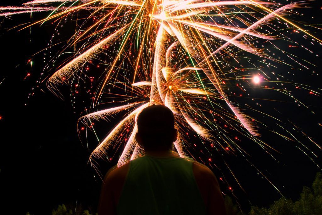 Image of a man looking up at fireworks in the night sky