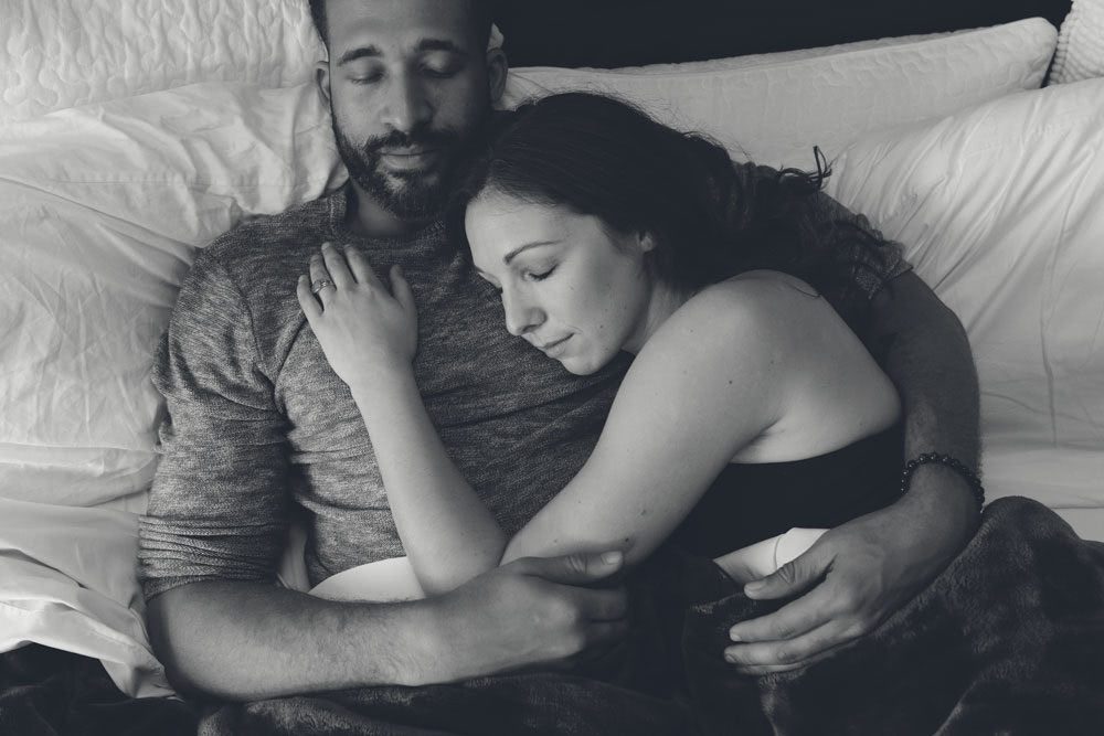 Black and white image of a couple laying together in bed with eyes closed symbolizing distress over sexual function problems